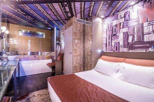 Schlafzimmer mit einem Bett, einer Badewanne und einem Waschbecken in der Unterkunft Apostrophe Hôtel in Paris