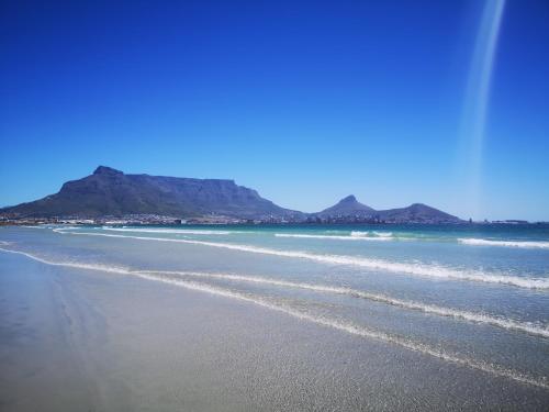 vistas a una playa con montañas en el fondo en Cape Town Family Beachfront Apartment Leisure Bay en Ciudad del Cabo
