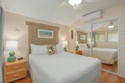 um quarto com uma cama branca e um espelho em Kona Isle C38 em Kailua-Kona