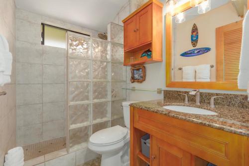 uma casa de banho com um WC, um lavatório e um espelho. em Kona Isle C38 em Kailua-Kona