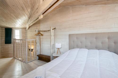 a bedroom with a white bed and a wooden wall at Petite maison de village Eloise proche de la plage in Sainte-Marie-de-Ré