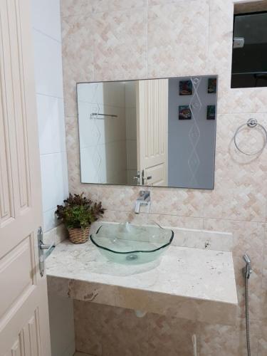 ein Badezimmer mit einem Glaswaschbecken und einem Spiegel in der Unterkunft Casa para temporada c/ ar condicionado, próximo da praia e do Beco das Garrafas in Prado