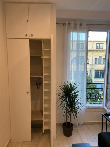 um quarto com um armário branco e uma planta em Studio sur avenue jean médecin à Nice em Nice