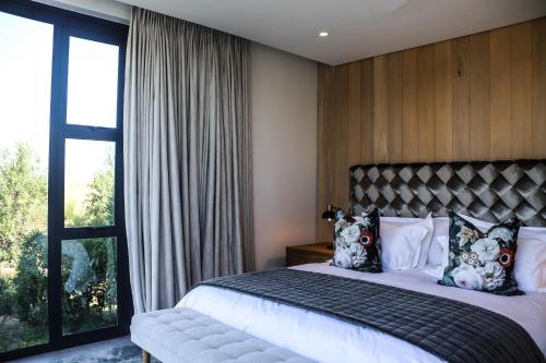 a bedroom with a bed and a large window at Vergenoegd Löw Boutique Hotel & Spa in Cape Town