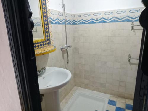 een badkamer met een wastafel, een toilet en een spiegel bij Soultana 4 pour les familles in Oualidia