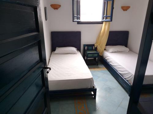 Duas camas num pequeno quarto com uma janela em Soultana 4 pour les familles em Oualidia