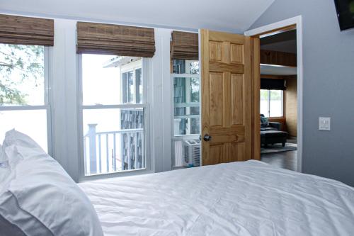 a bedroom with a white bed and two windows at Lake Winnisquam Getaway in Sanbornton