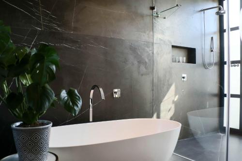 a bathroom with a white bath tub and a plant at Vergenoegd Löw Boutique Hotel & Spa in Cape Town