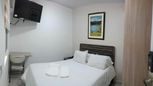 a bedroom with a white bed with a tv on the wall at Casa Jac in Bucaramanga