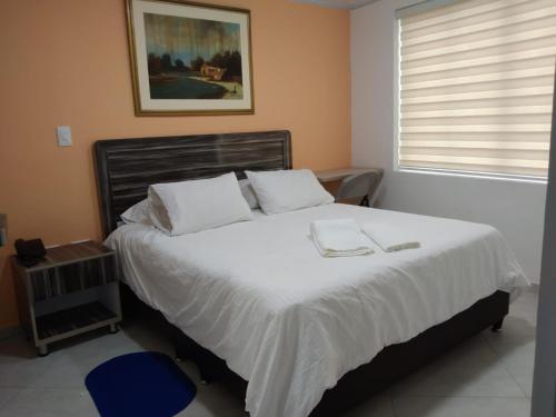 a bedroom with a large bed with white sheets at Casa Jac in Bucaramanga