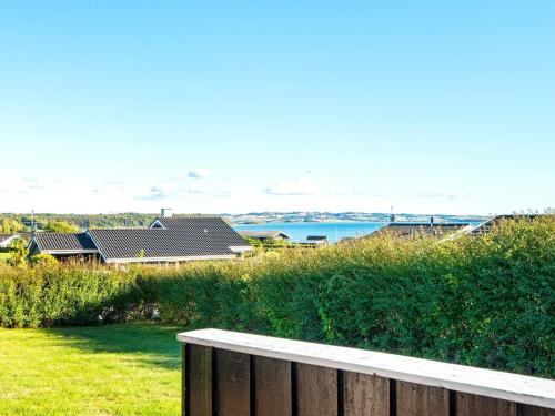 a wooden fence in front of a yard with a house at 6 person holiday home in R nde in Rønde