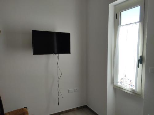 TV de pantalla plana colgada en una pared junto a una ventana en Piccola LoLu en Ortona