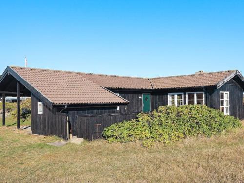 a black building with a green door in a field at 4 person holiday home in Skagen-By Traum in Skagen
