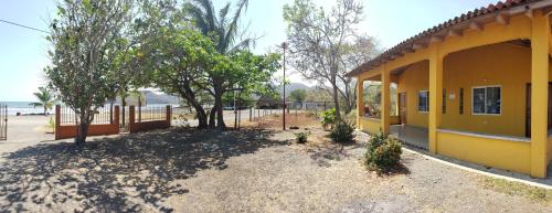 a yellow building with trees in front of it at cabañas playa guanico in Tonosí