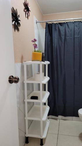 apartamento 407 zona 9 في غواتيمالا: رف أبيض في حمام مع ستارة دش زرقاء