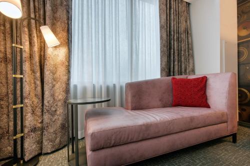a pink couch with a red pillow in a room at Cambria Hotel Nashville Downtown in Nashville
