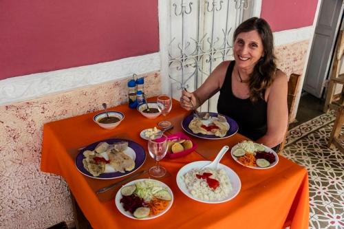 a woman sitting at a table with plates of food at Hostal del Pino Appartement 1 in Trinidad