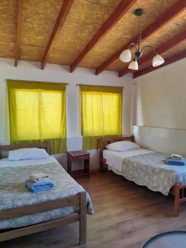 two beds in a room with yellow curtains at Cabañas el Chañar in San Pedro de Atacama