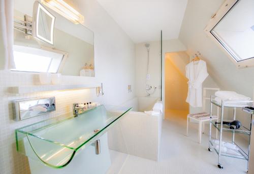 La salle de bains est pourvue d'un comptoir en verre et d'un lavabo. dans l'établissement Hôtel La Pérouse, à Nantes