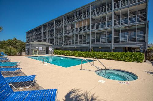 a building with a swimming pool in front of a building at Bella Vista: Marshfront Condo 1 Block To The Beach. Pool & Hot Tub-1st Floor in Murrells Inlet