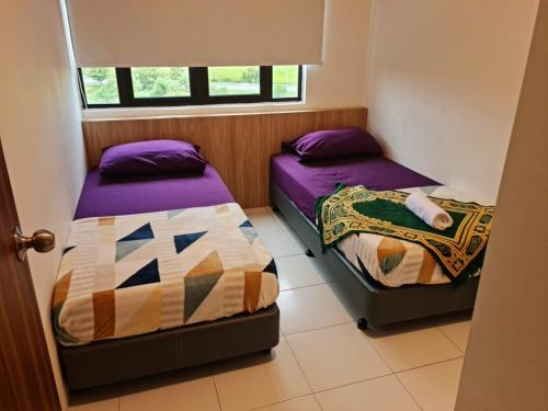 two beds in a small room with purple sheets at Professional HomeStay D' Alor Setar in Alor Setar