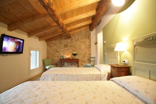 a bedroom with two beds and a flat screen tv at Bed & Breakfast Le Coste in Lazise