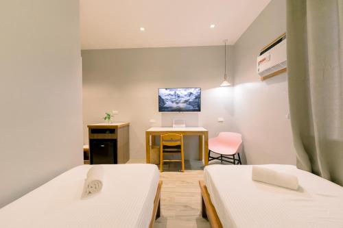 Habitación con 2 camas y TV en la pared. en Madonna Hometel and Suites New Pandan en Panabo