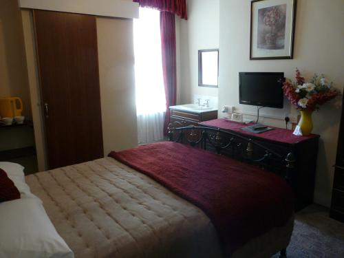 a bedroom with a bed and a television on a desk at Melbourne Guest House in Rhyl