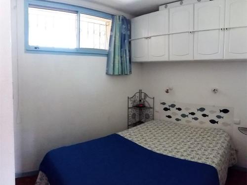 une chambre avec un lit avec une couverture bleue et une fenêtre dans l'établissement Appartement T2 avec piscine, parking privé, proche plage - 4 couchages - Argelès-sur-Mer - FR-1-388-8, à Argelès-sur-Mer