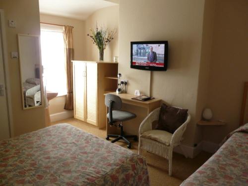 a hotel room with a bed and a desk and a television at Melbourne Guest House in Rhyl