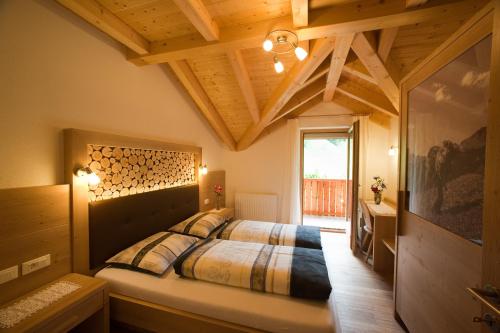 una camera da letto con un letto grande con soffitto in legno di Lüch da Mirió a La Valle