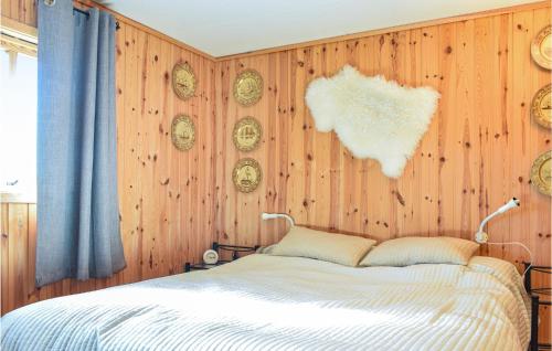 a bedroom with a bed and a wooden wall with clocks at Stunning Home In Haulandshella With 3 Bedrooms And Sauna in Tveitevåg