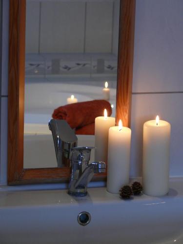two candles sitting on a bathroom sink in front of a mirror at Domek Kozacki in Łukowe