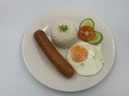 a white plate with an egg and a sausage and rice at Madonna Hometel and Suites New Pandan in Panabo