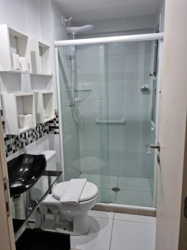 a bathroom with a toilet and a glass shower at Apartamento na praia de Jatiúca com piscina e área de lazer in Maceió