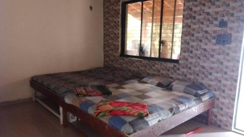 a small bed in a room with a brick wall at Tendulkar Beach Resort in Diveagar