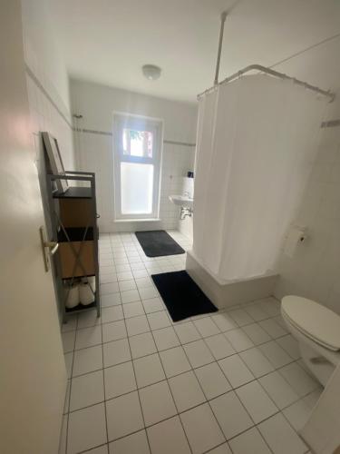 La salle de bains est pourvue de carrelage blanc, de toilettes et d'une fenêtre. dans l'établissement Osthafen II, à Berlin