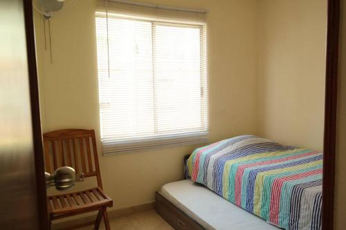 1 dormitorio con cama, ventana y silla en Casa Anillo vía, cerca a CC Cañaveral y Clínica, en Floridablanca