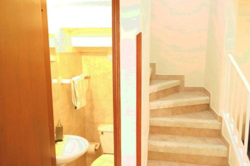 a bathroom with a toilet a sink and a staircase at Casa Anillo vía, cerca a CC Cañaveral y Clínica in Floridablanca