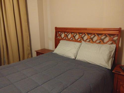 a bed with a wooden headboard in a bedroom at Departamento Los Andes in Los Andes