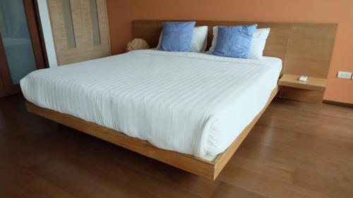 a bedroom with a large white bed with blue pillows at Baan Chan Talay - D32 A modern comfortable 2 bedroom apartment in Chaam in Ban Bang Sai Yoi