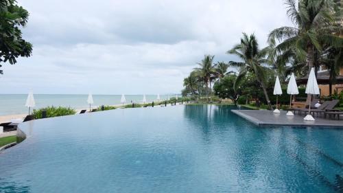 a large swimming pool next to the ocean at Baan Chan Talay - D32 A modern comfortable 2 bedroom apartment in Chaam in Ban Bang Sai Yoi