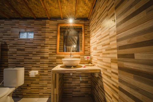 a bathroom with a sink and a mirror and a toilet at Hotra Hill Cottage in Nusa Penida