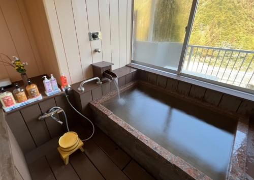a bath tub with a faucet in a bathroom at Hinotani Onsen Misugi Resort in Tsu