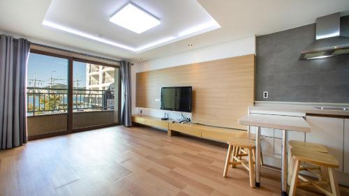 a kitchen with a table and a tv in a room at Carib Condo Hotel in Tongyeong