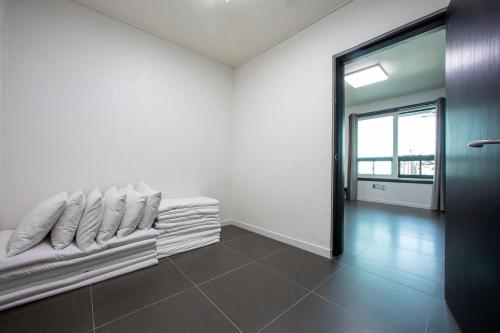 a white room with a couch with pillows on it at Carib Condo Hotel in Tongyeong