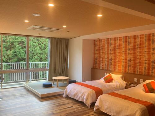 a hotel room with two beds and a balcony at Hinotani Onsen Misugi Resort in Tsu