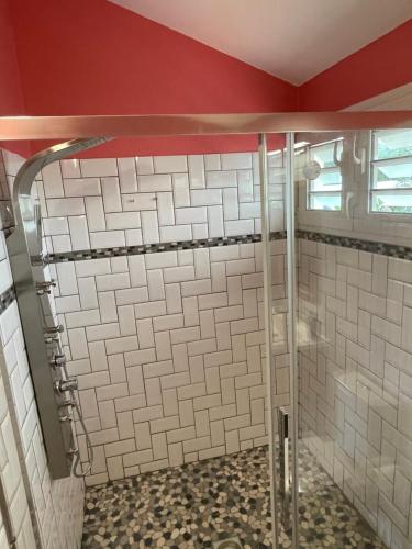 a shower in a bathroom with white tiles at Villa Norah t5 duplex in Le Robert