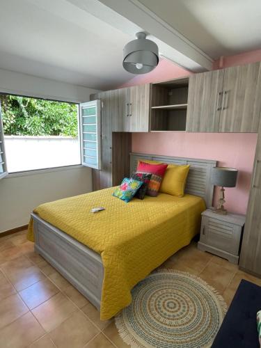 1 dormitorio con 1 cama con colcha amarilla y ventana en Villa Norah t5 duplex, en Le Robert