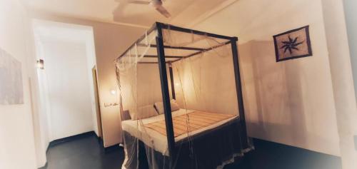 Cette chambre comprend un lit à baldaquin. dans l'établissement Sundance Surf Coconut Point, à Weligama